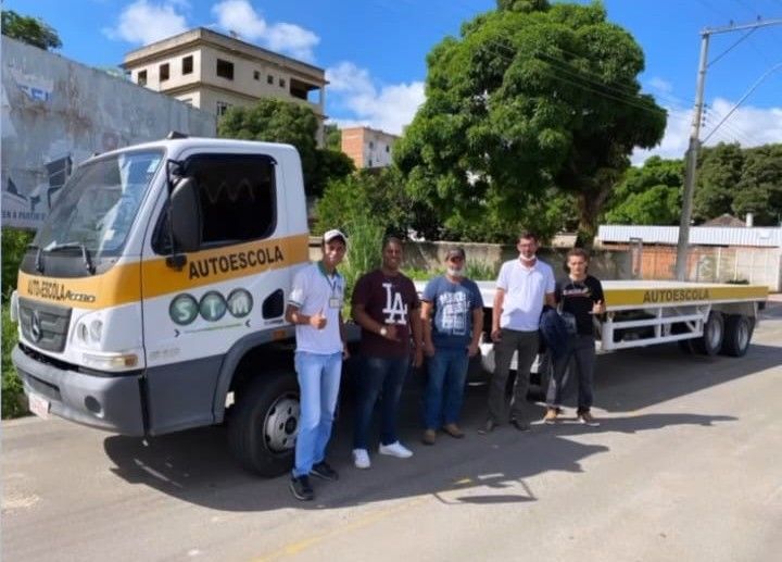 Alunos aprovados ao lado do caminhão prancha da Auto Escola SIM