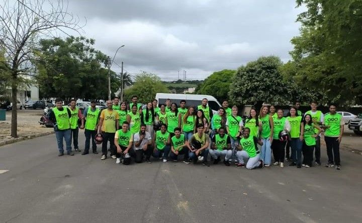 Turma numerosa de alunos aprovados da Auto Escola SIM, de colete verde, reunida na rua