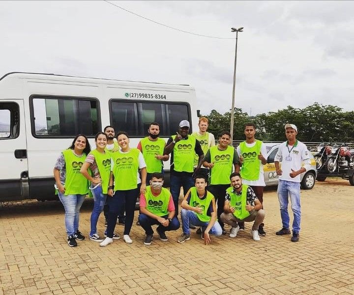 Turma de alunos aprovados posando com a van e as motocicletas da Auto Escola SIM